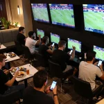 Engaged bettors enjoying ALO8 live action in a vibrant sports lounge with screens